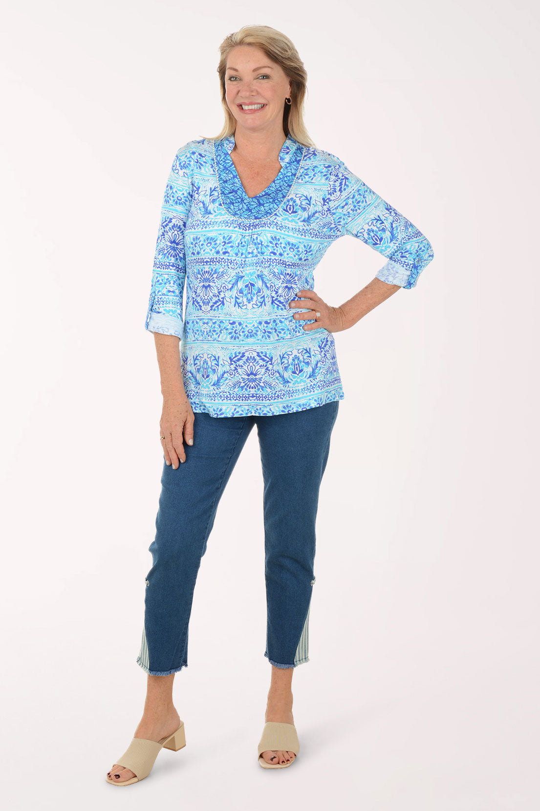 Woman wearing a blue patterned top and blue pants on a white background