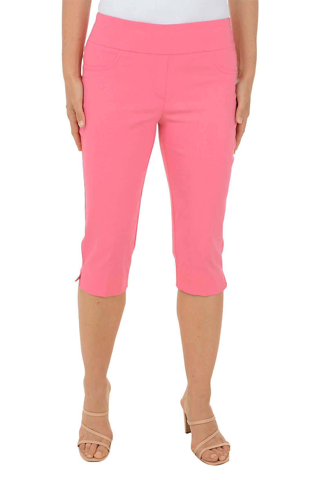 A front shot of a model wearing a pair of pink pull-on clamdigger pants with a 3-inch wide elasticized waistband, faux front pockets, back patch pockets, faux fly, straight hemline with side slits, and a mid-rise design.