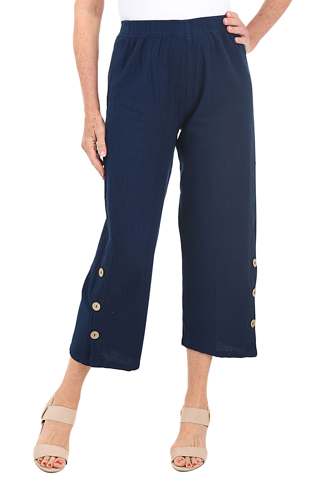 A front shot of a model wearing a pair of navy capri pants with side button detail on the hemline, made of crinkle cotton fabric.