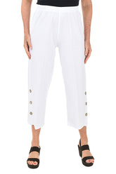 A front shot of a model wearing a pair of white capri pants with side button detail on the hemline, made of crinkle cotton fabric.