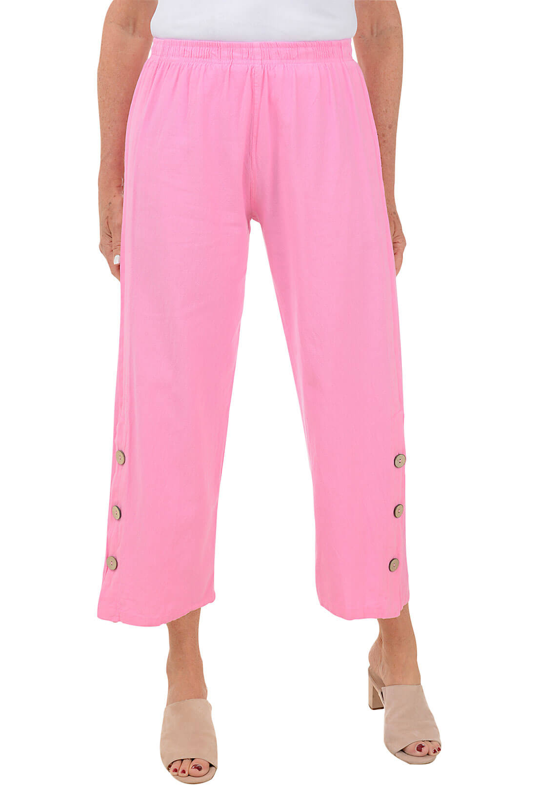 A front shot of a model wearing a pair of  pink capri pants with side button detail on the hemline, made of crinkle cotton fabric.