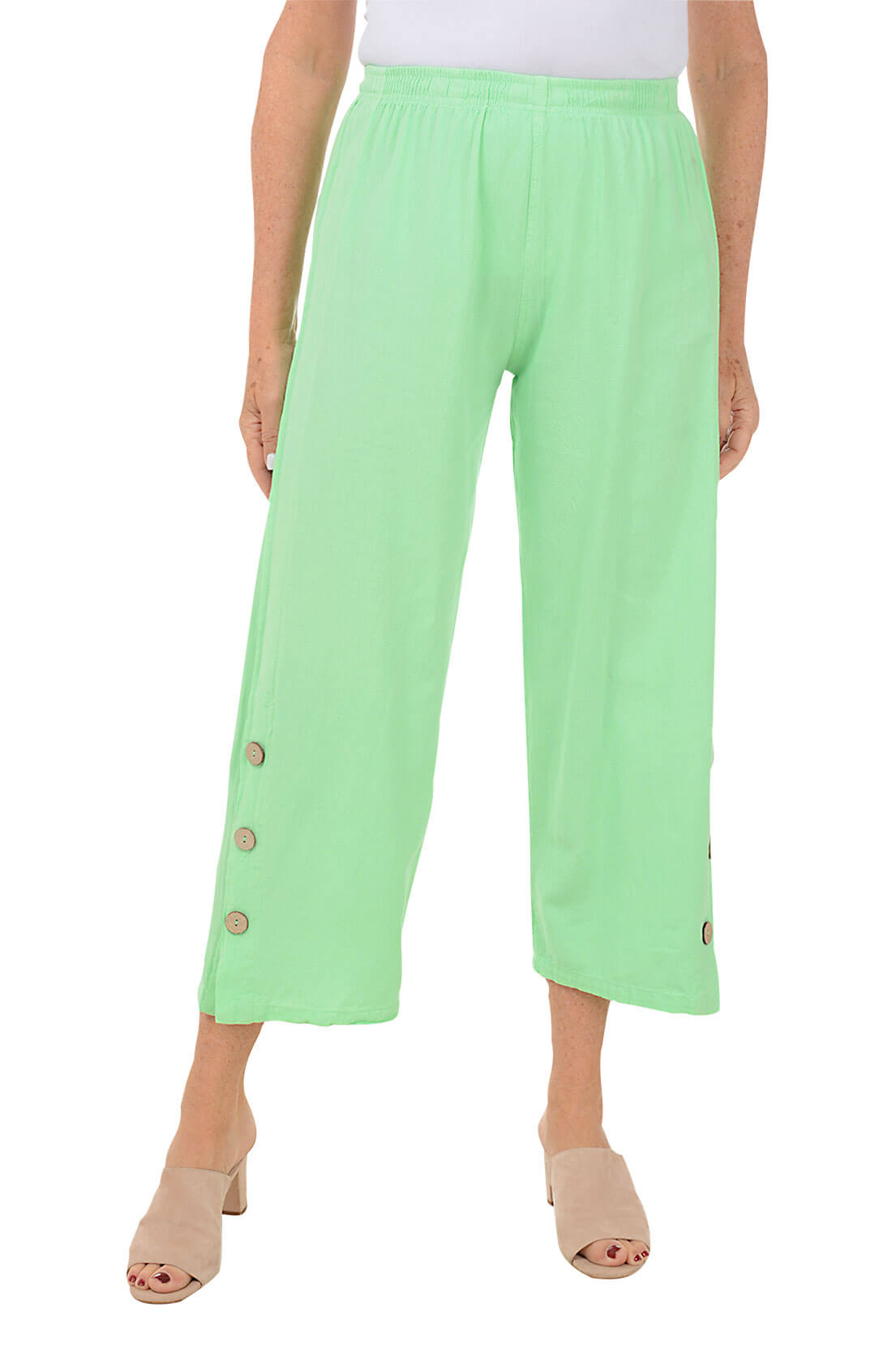A front shot of a model wearing a pair of green capri pants with side button detail on the hemline, made of crinkle cotton fabric.