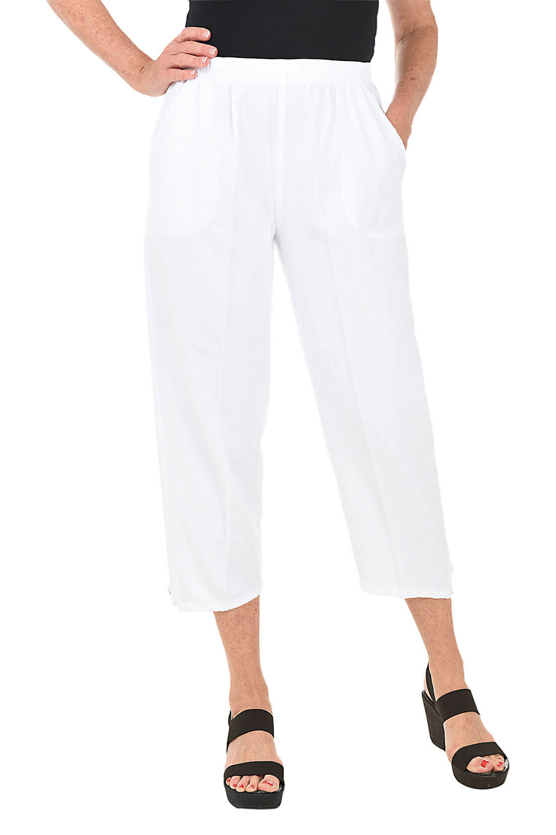 A front shot of a model wearing a pair of white capri pants with button-tab detail on the hemline, made of crinkle cotton fabric, with an elastic waistband and side pockets.