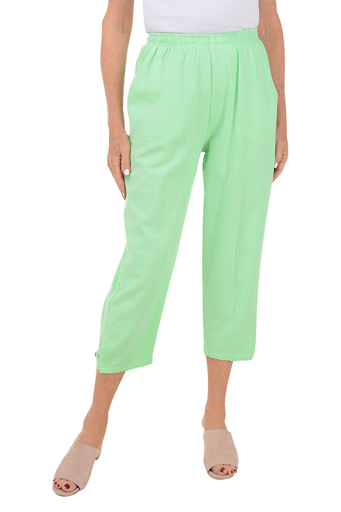 A front shot of a model wearing a pair of green capri pants with button-tab detail on the hemline, made of crinkle cotton fabric, with an elastic waistband and side pockets.