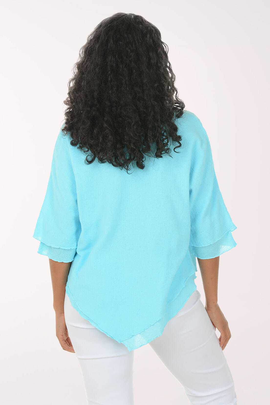 Back shot of a woman wearing a light blue top and white pants on a white background