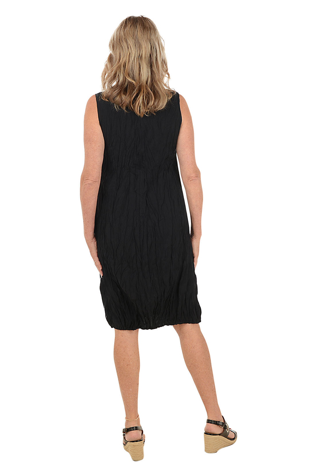 Woman wearing a black and white sleeveless dress with a pocket on the left side and an asymmetrical hem. Back shot.