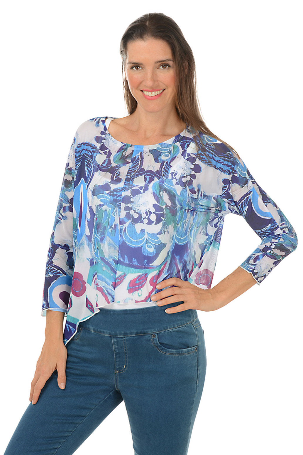 A front shot of a model wearing a multicolored floral asymmetrical top with long sleeves and a scoop neckline, paired with blue jeans.