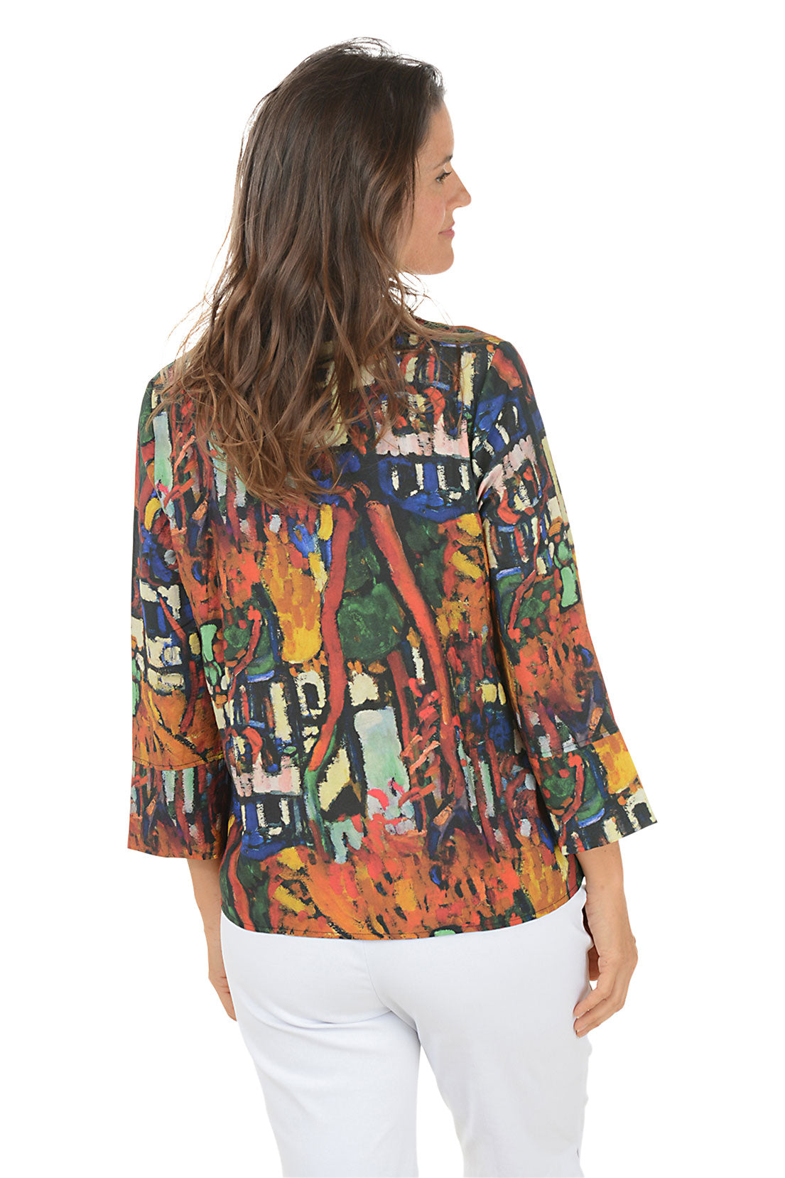 Woman wearing a colorful patterned blouse with white pants on a white background. Back shot.