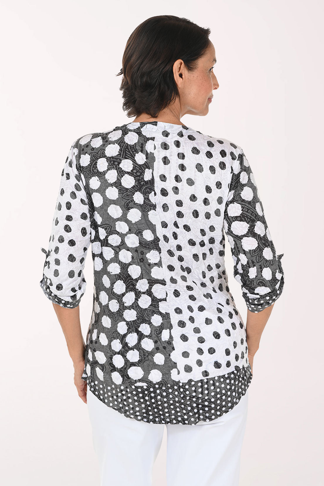 Woman wearing a 3/4 sleeve v-neck black and white polka dot top
