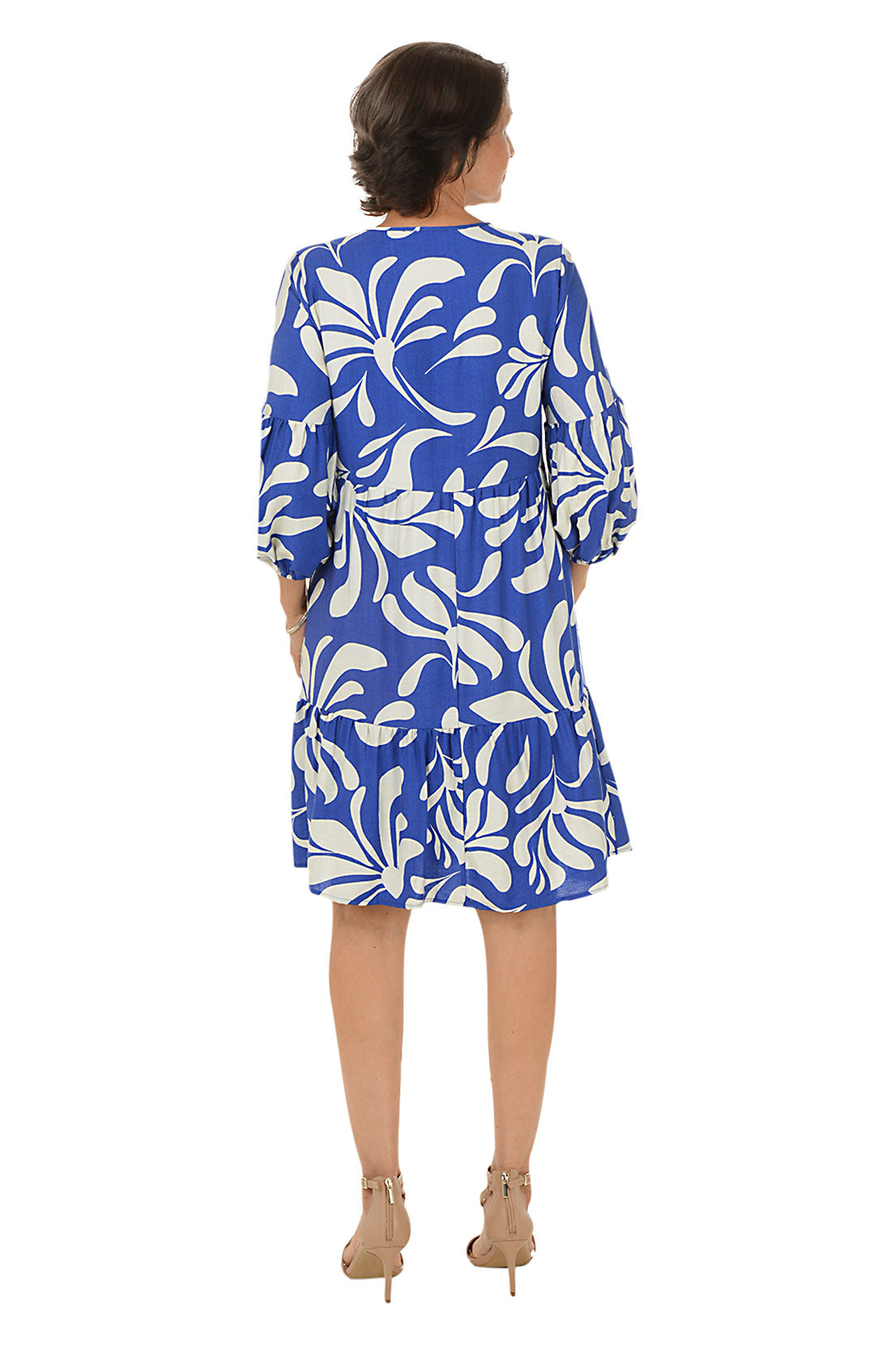 Woman wearing a blue and white patterned dress on a white background. Back shot.
