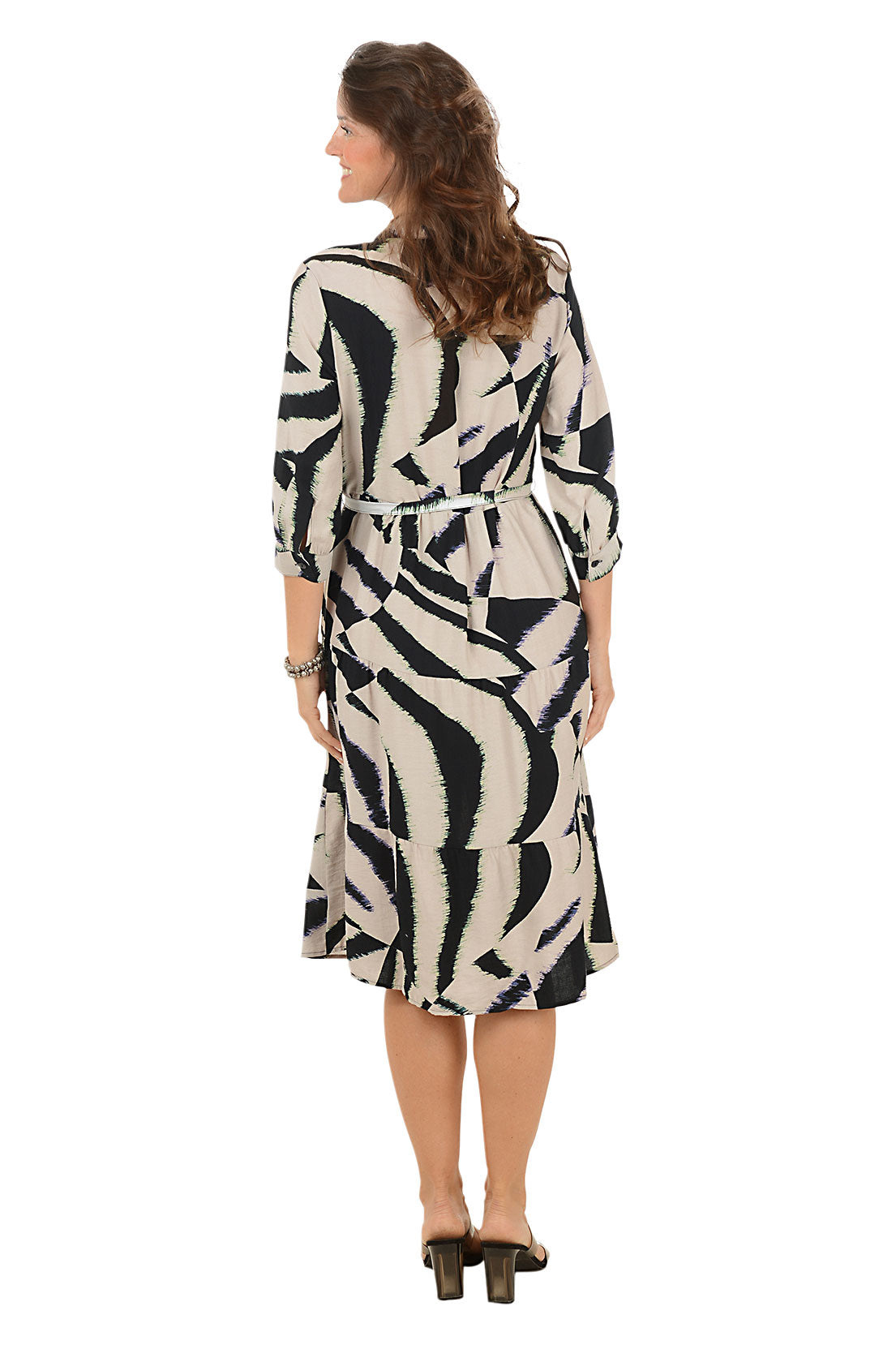 Woman wearing a black and brown patterned dress on a white background. Back shot.