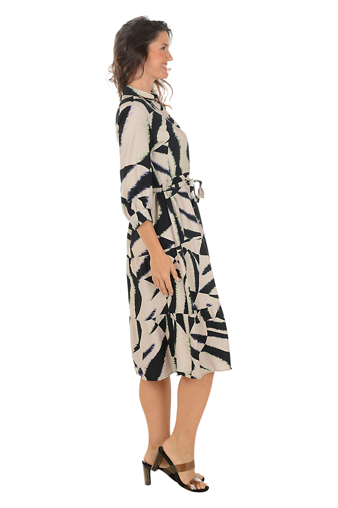 Woman wearing a black and brown patterned dress on a white background. Side shot.