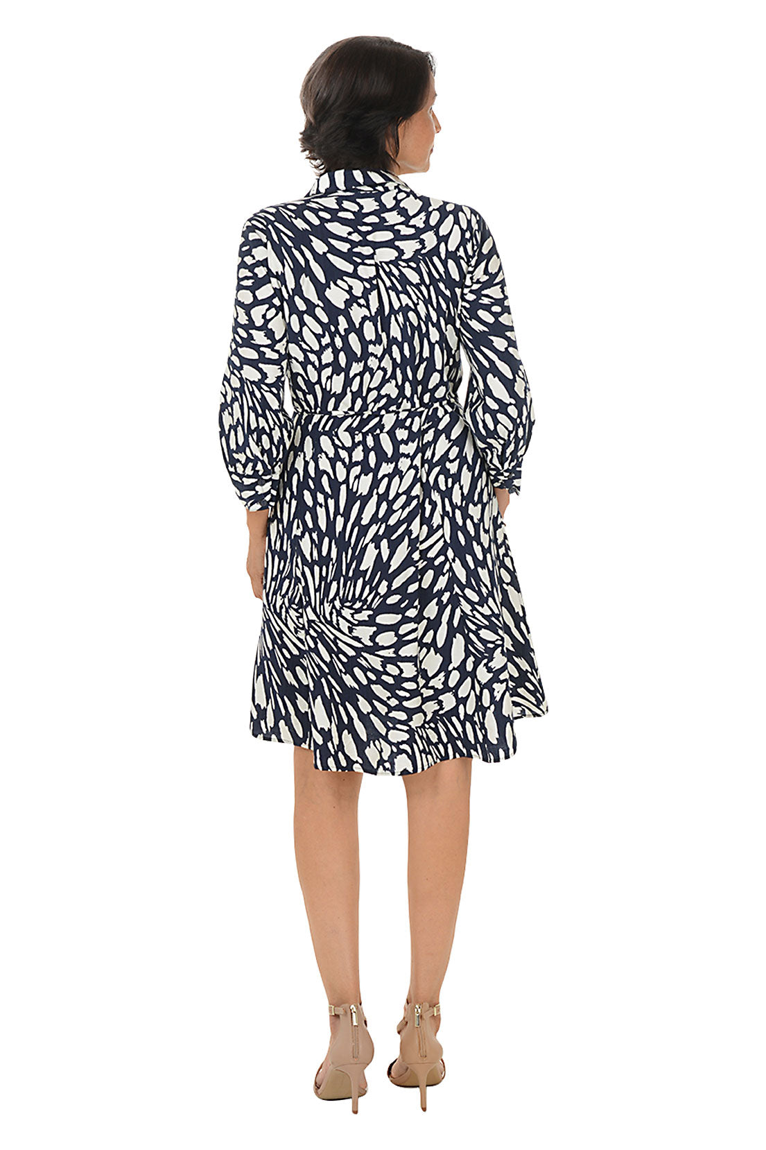 Woman wearing a navy and white patterned dress on a white background. Back shot.