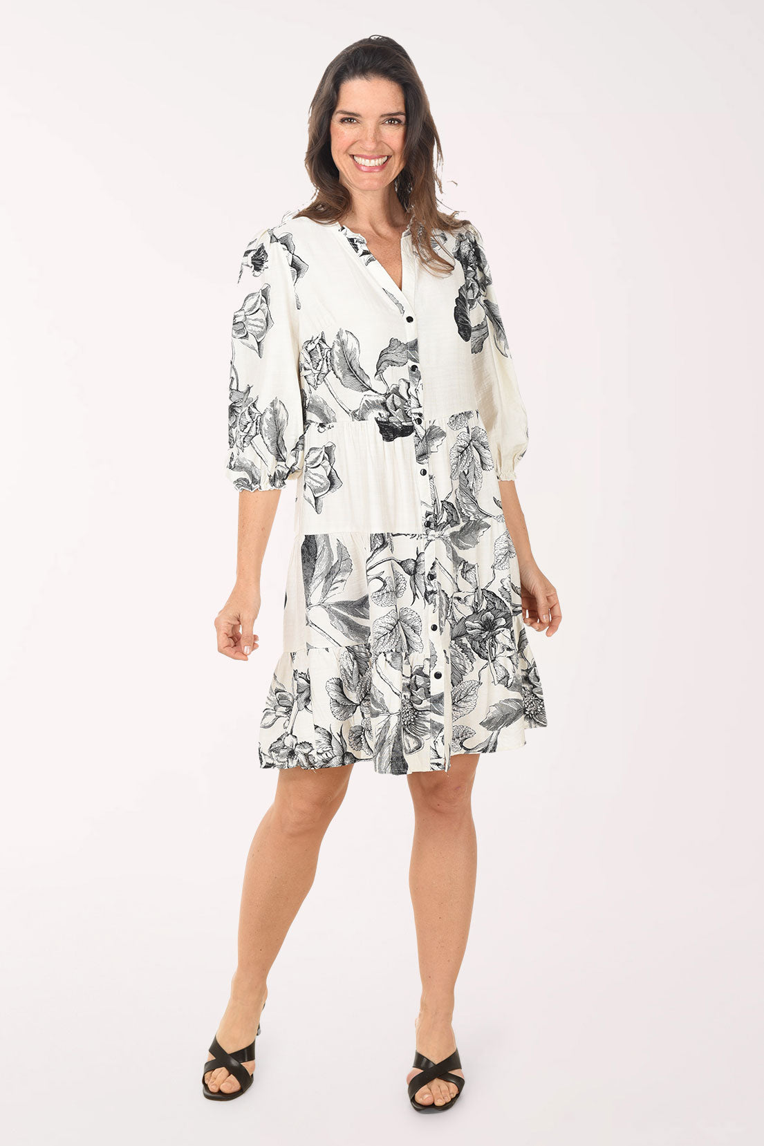 Woman wearing a white dress with black floral pattern on a white background