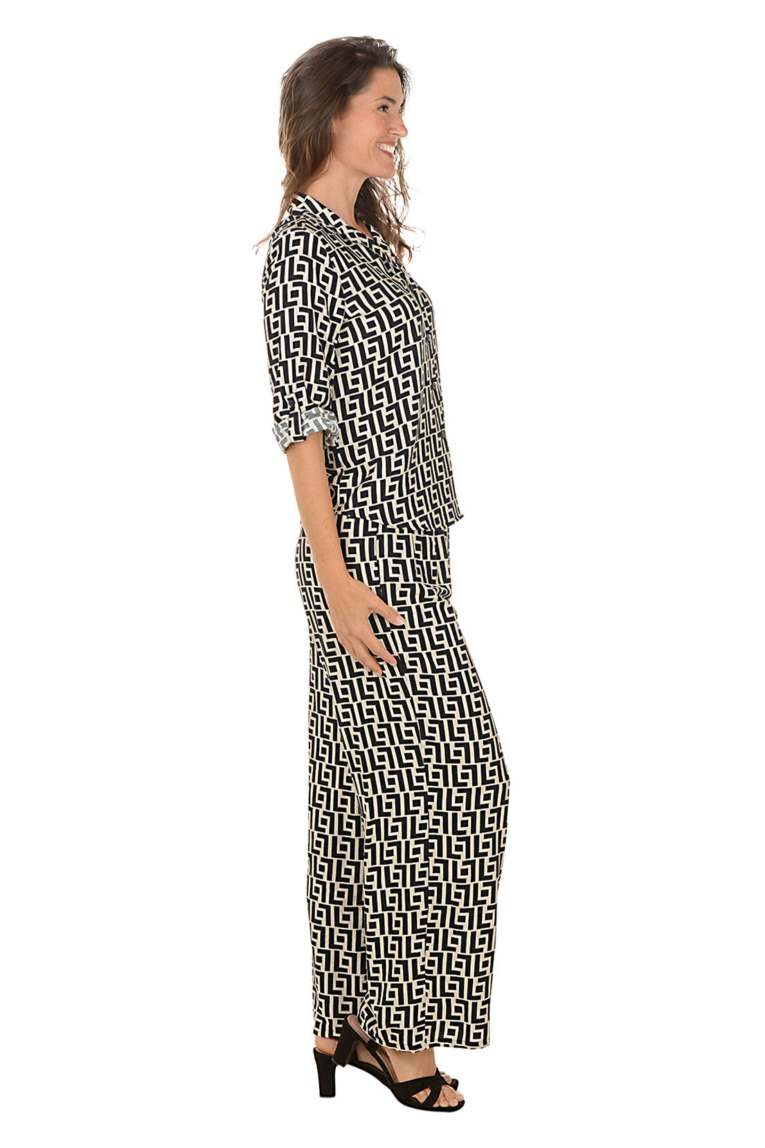 Woman wearing a geometric black and white patterned lounge set on a white background. Side shot.