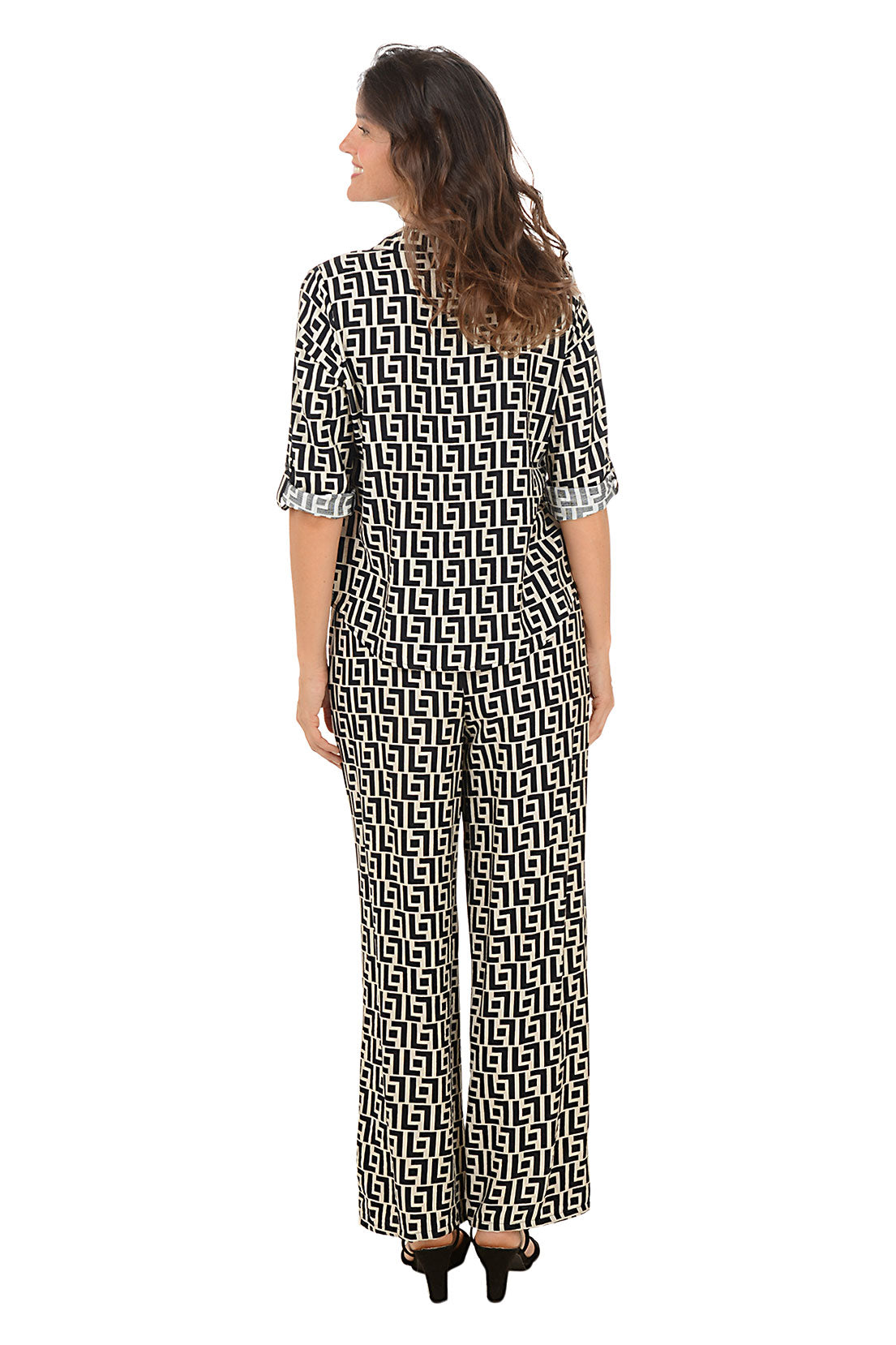 Woman wearing a geometric black and white patterned lounge set on a white background. Back shot.