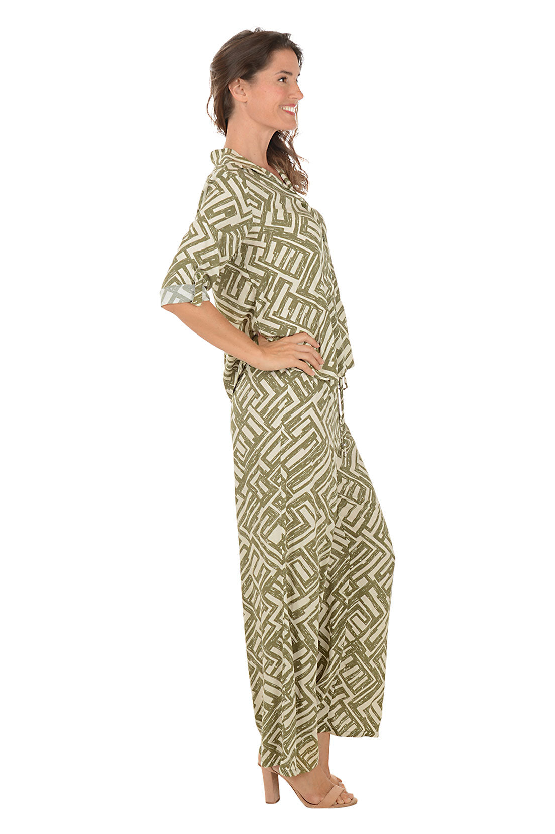 Woman wearing a green patterned lounge set on a white background. Side shot.