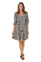 Woman wearing a black and khaki 3/4 sleeve crackle patterned dress on a white background.