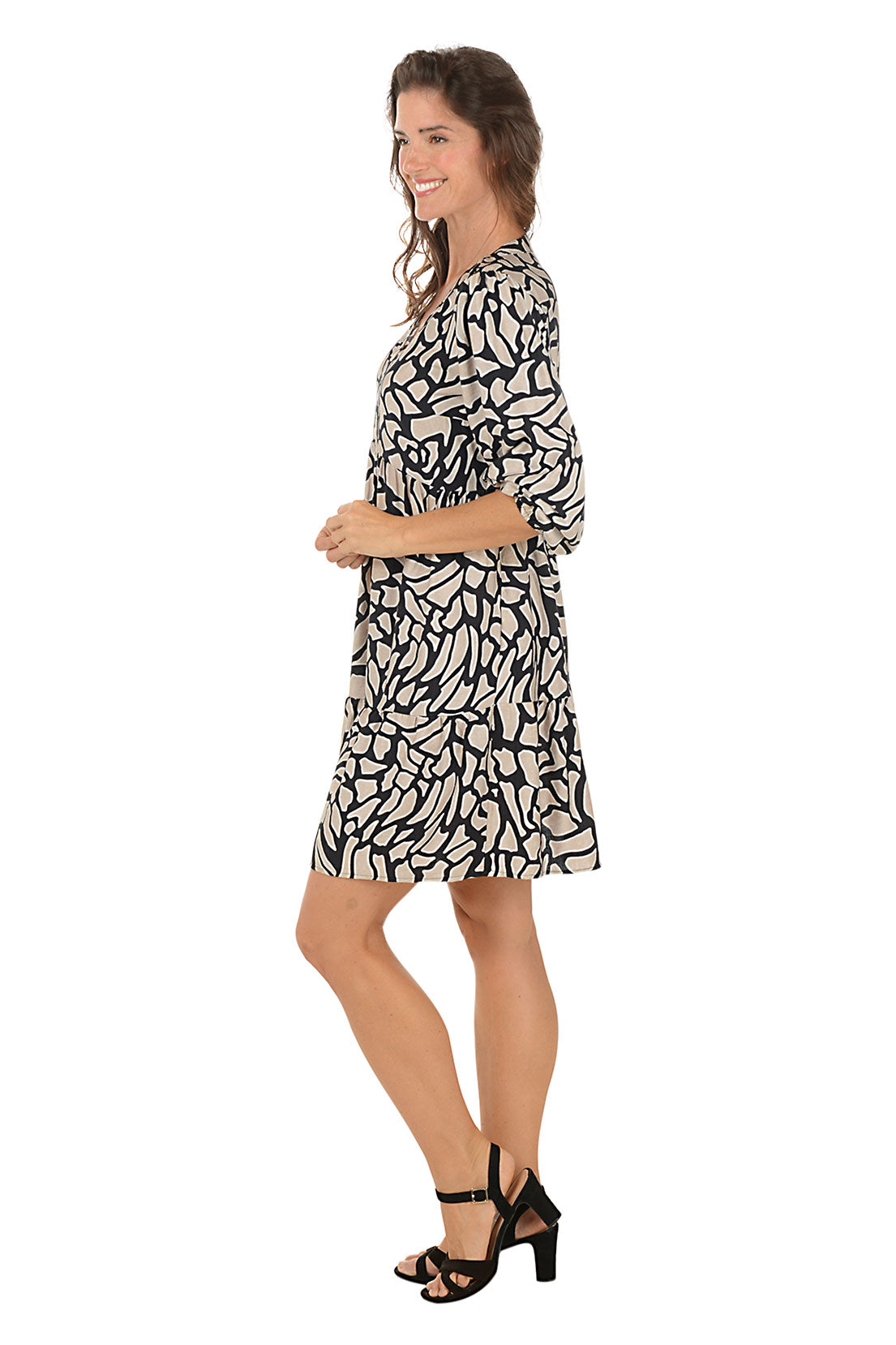 Woman wearing a black and khaki 3/4 sleeve crackle patterned dress on a white background. Side shot.