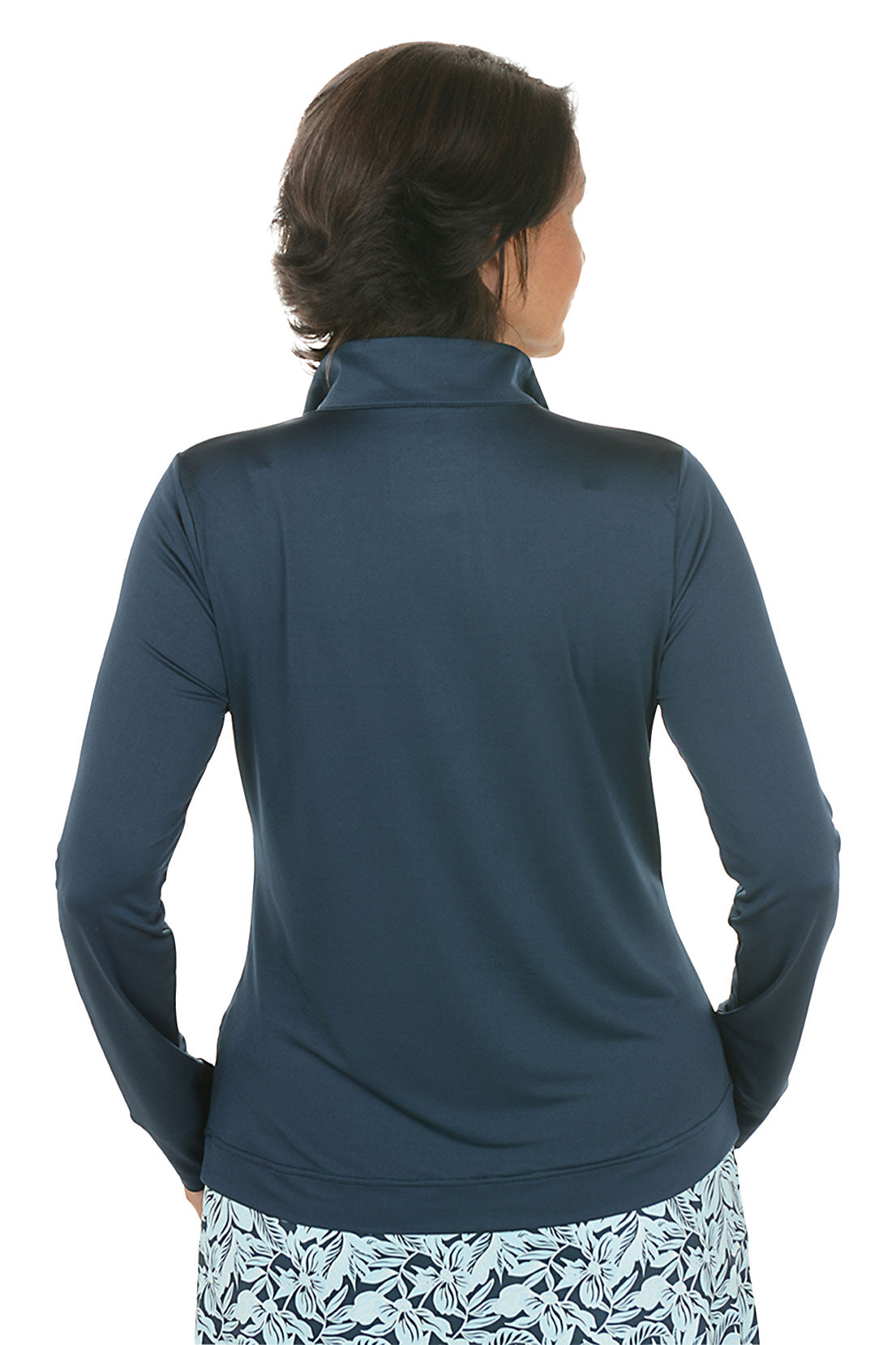 Woman wearing a navy long-sleeve top with a floral skirt on a white background. Back shot.