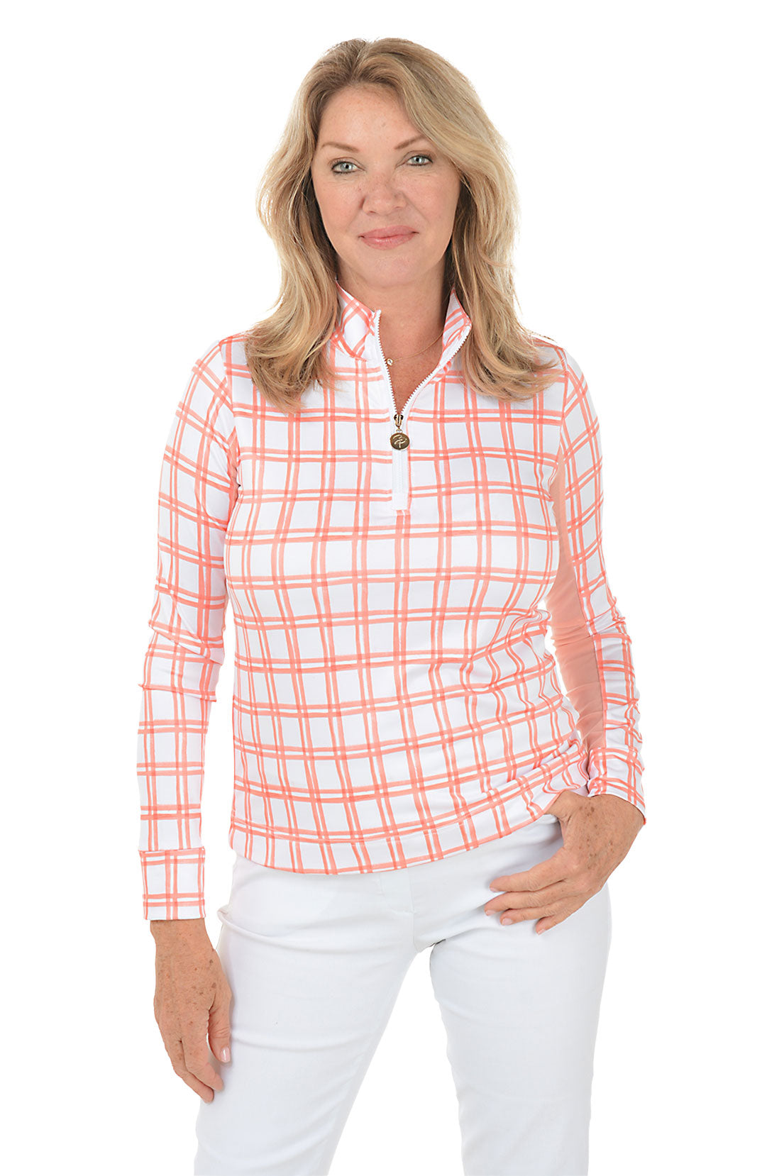 A front shot of a model wearing a peach and white windowpane plaid mock neck sun shirt with long sleeves and white pants.