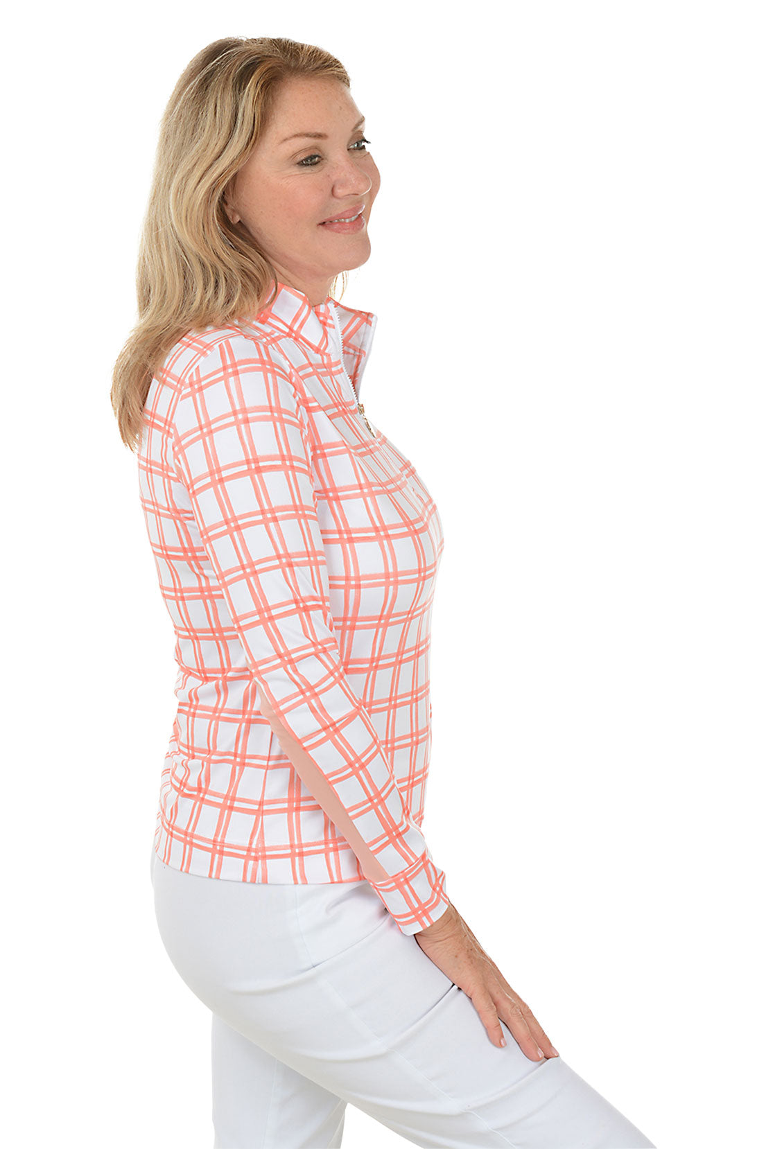 A side shot of a model wearing a peach and white windowpane plaid mock neck sun shirt with long sleeves and white pants.