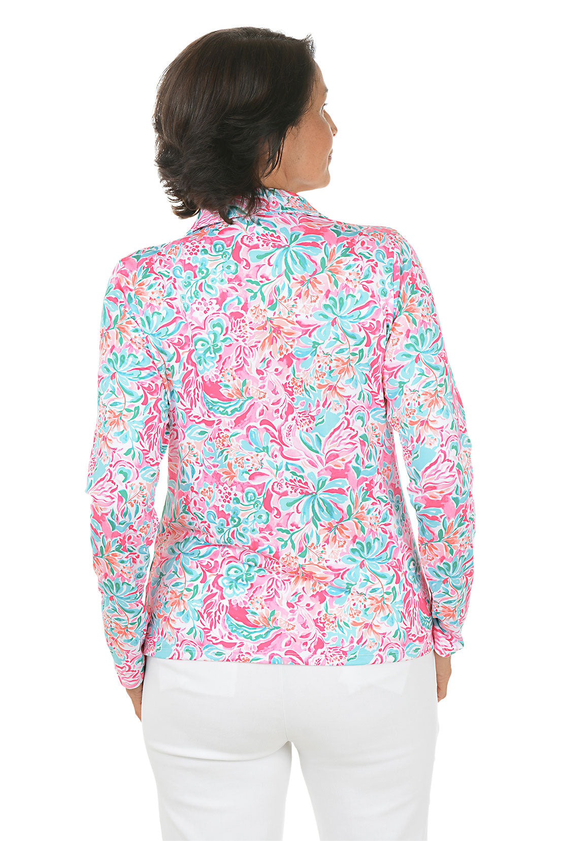 Woman wearing a colorful floral blouse with white pants on a white background. Back shot.