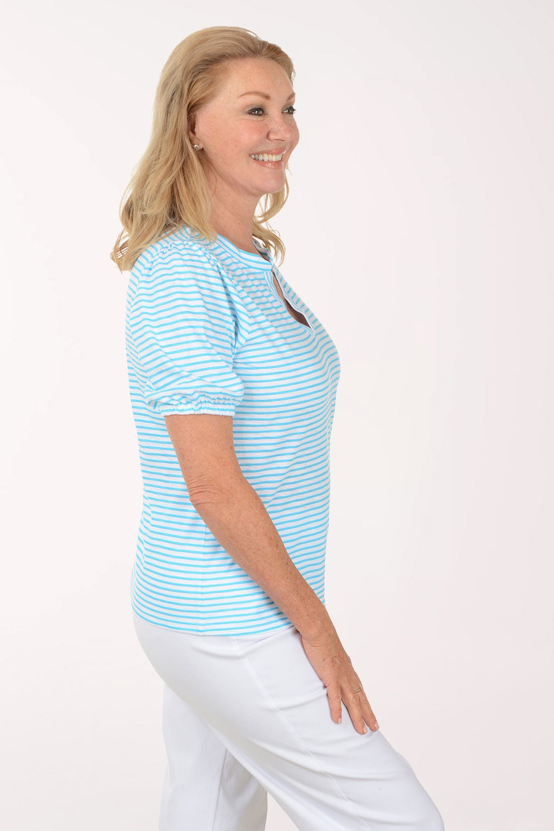 Woman wearing a light blue striped shirt and white pants on a white background