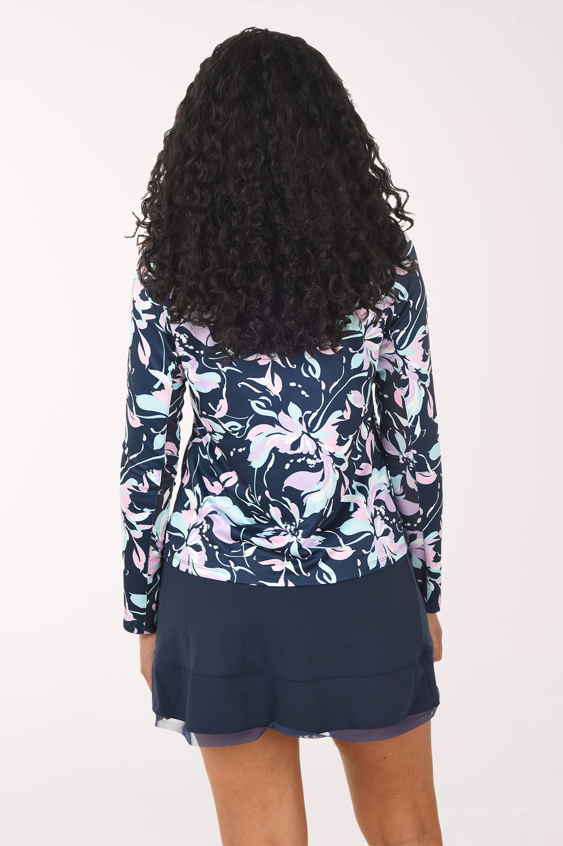 Woman wearing a floral long-sleeve top and navy skirt on a white background