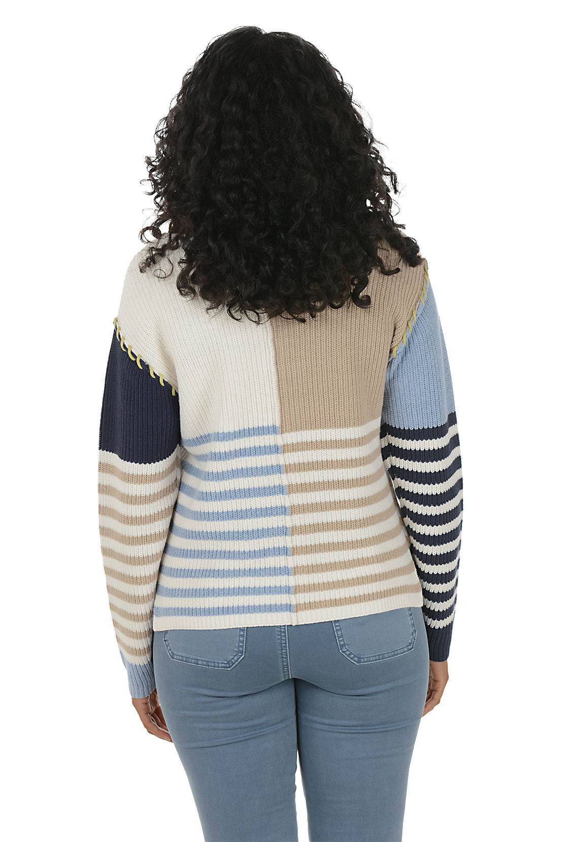 Woman wearing a colorful patchwork sweater boat neck sweater with blue jeans on a white background. Back shot.