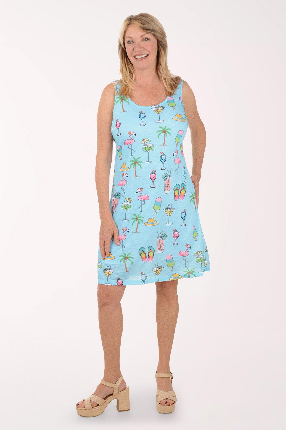 Woman wearing a light blue sleeveless dress with colorful summer-themed print on a white background