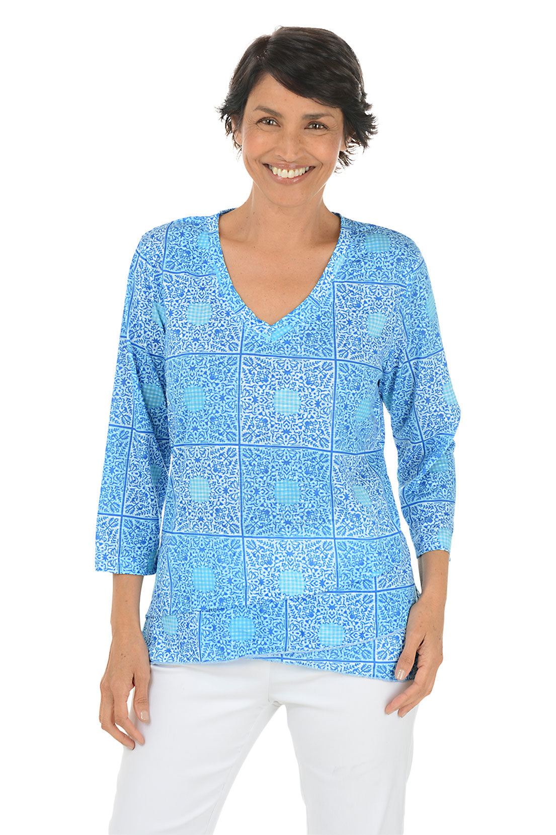 A front shot of a model wearing a blue and white checkered bandana tunic with a V-neck and 3/4 sleeves, paired with white pants.