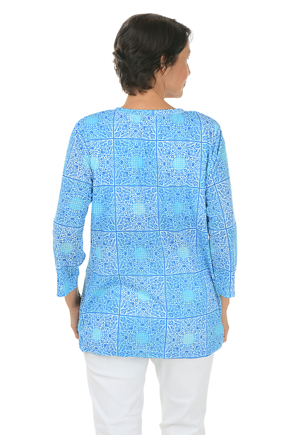 A back shot of a model wearing a blue and white checkered bandana tunic with a V-neck and 3/4 sleeves, paired with white pants.