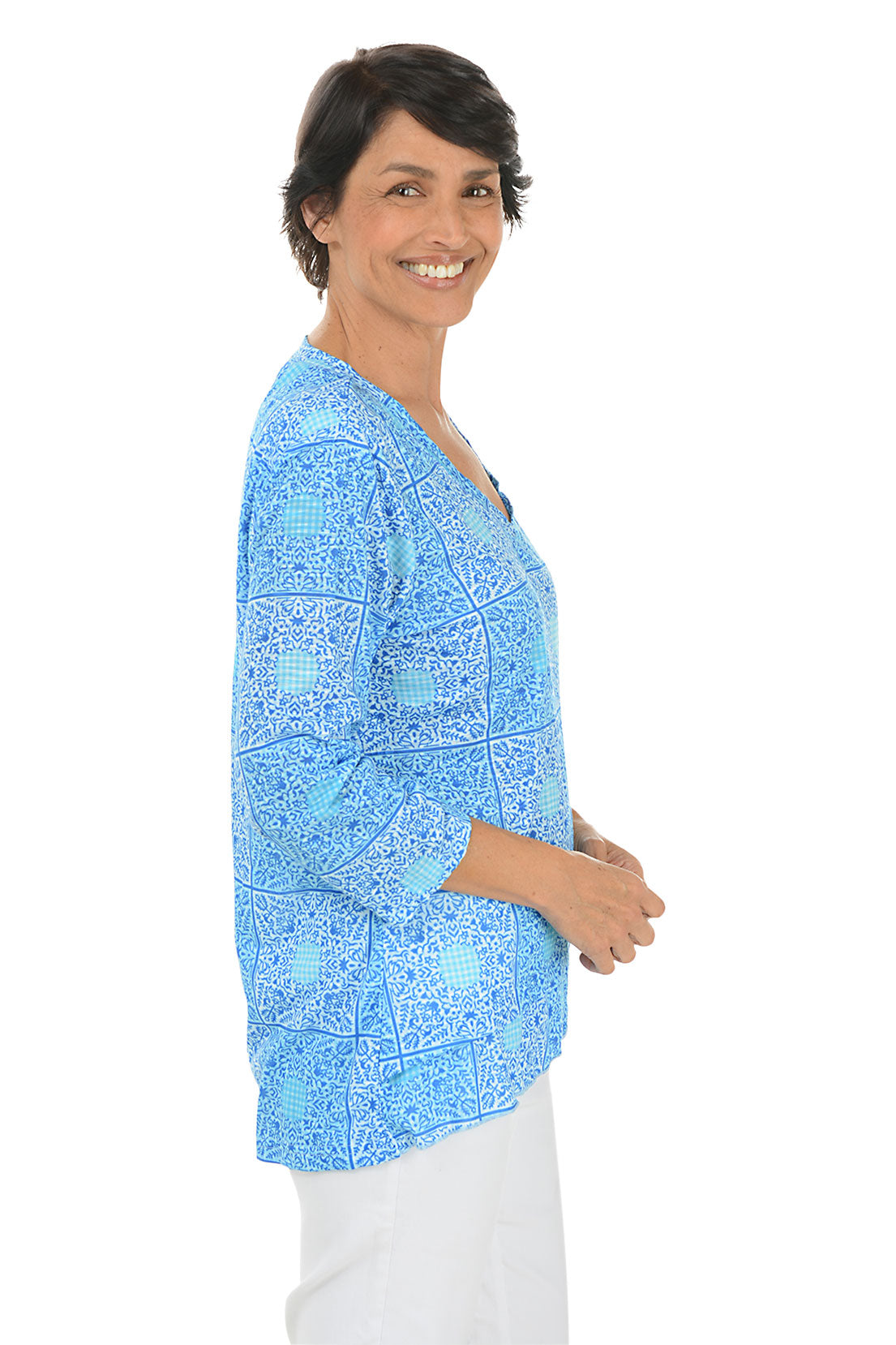 A side shot of a model wearing a blue and white checkered bandana tunic with a V-neck and 3/4 sleeves, paired with white pants.