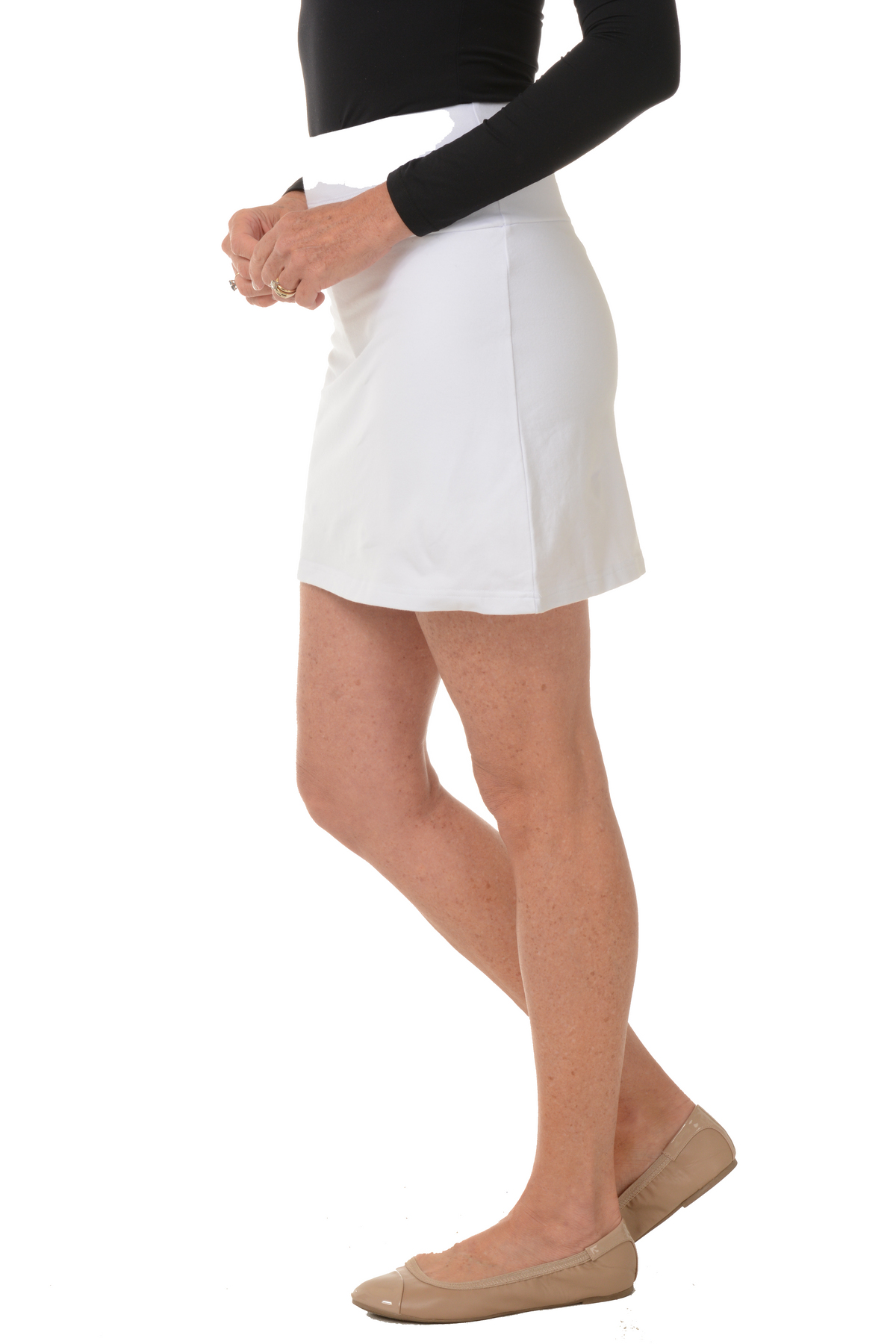 A side shot of a model wearing a white pull-on skort with a straight hemline and an elasticized waistband.