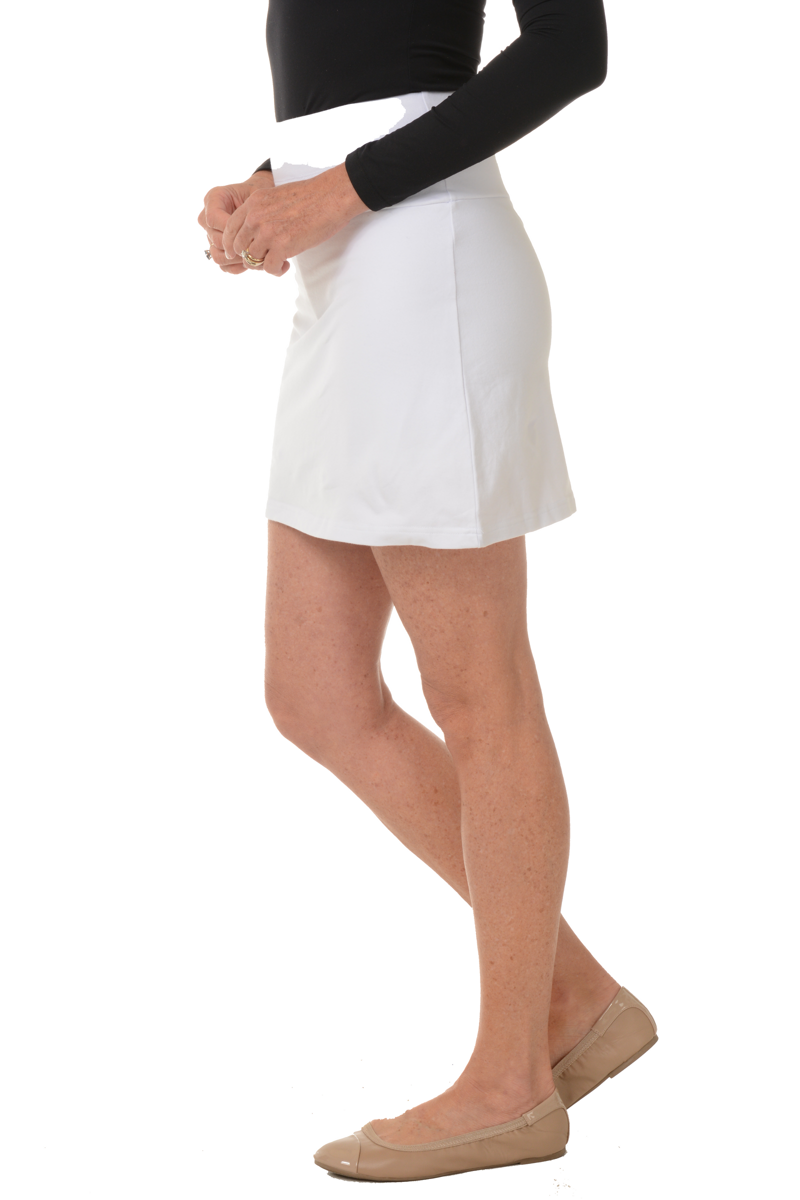 A side shot of a model wearing a white pull-on skort with a straight hemline and an elasticized waistband.