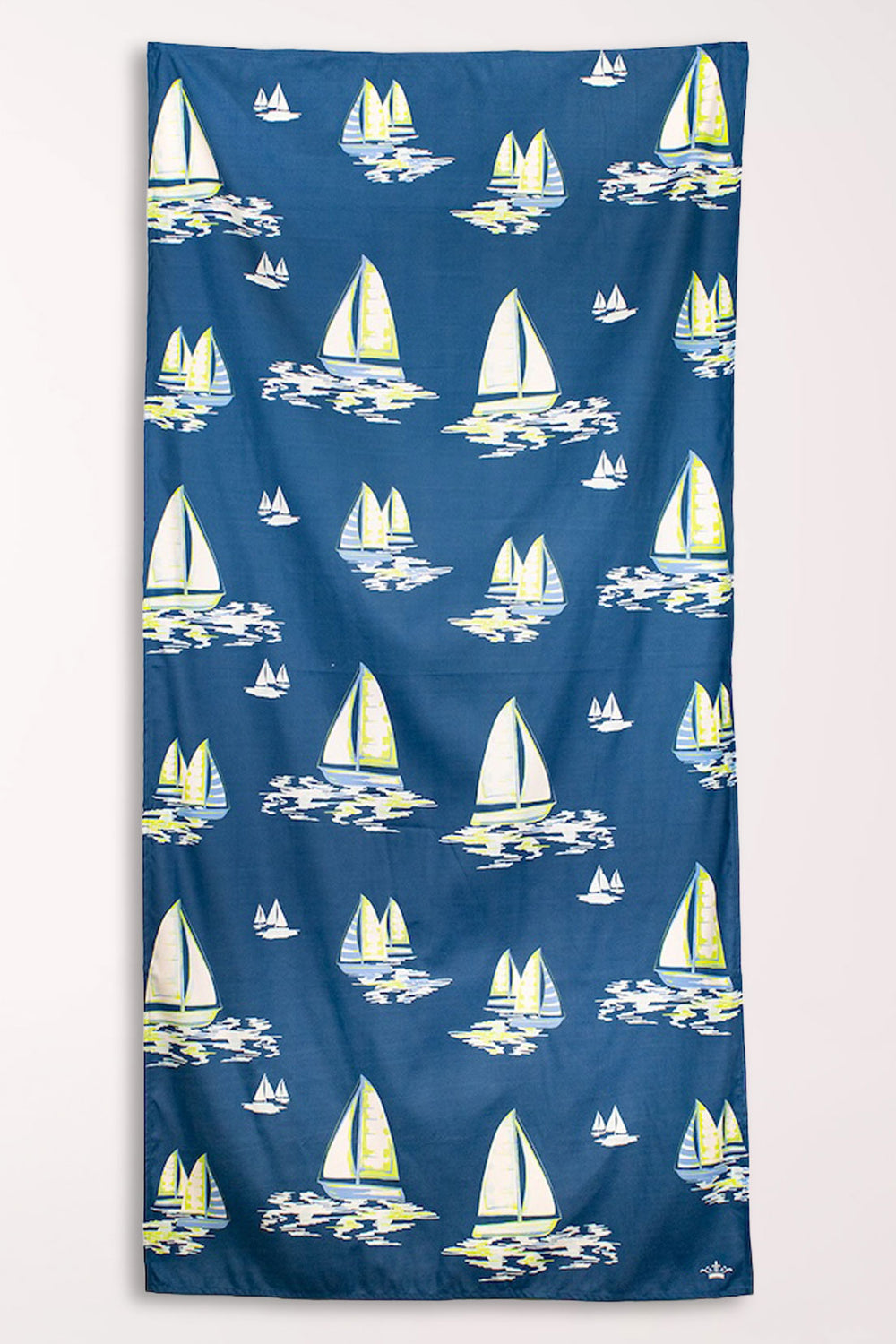 Navy blue microfiber beach towel covered in white and yellow sailboats on painted waves, shown hanging flat.