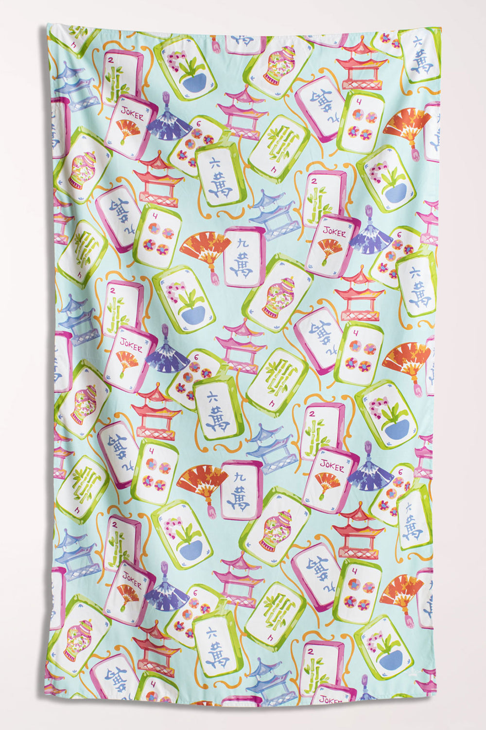 Microfiber beach towel covered in mahjong tiles, pagodas, and paper fans in pink, green, periwinkle, and coral on a pale aqua background.