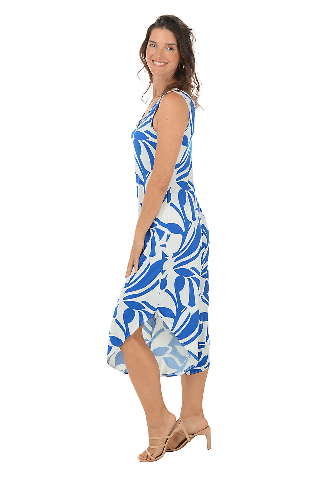 A side shot of a model wearing a sleeveless jumpsuit with a floral pattern in blue and white colors, featuring a V-neckline and wide, cropped leg with an angled hem.