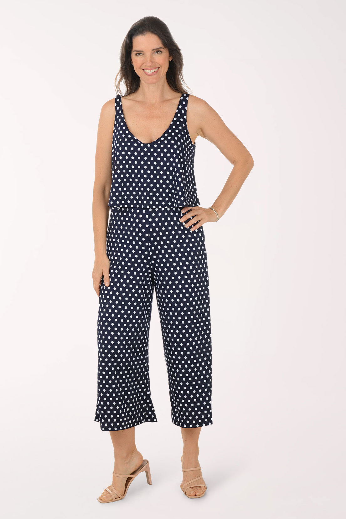 Woman wearing a navy blue jumpsuit with white polka dots on a white background