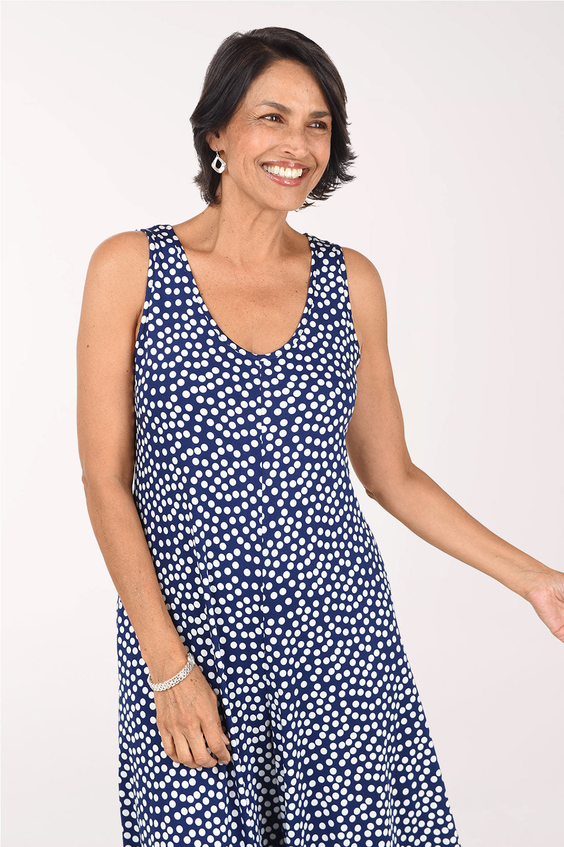 Close-up front view of the navy polka dot jumpsuit showing the V-neckline, wide sleeveless straps and the all-over white dot print