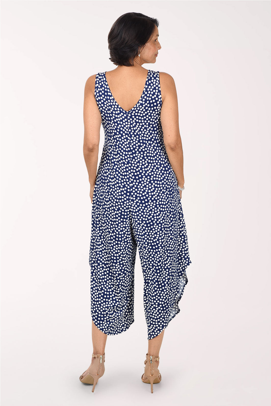 Back view of the navy polka dot jumpsuit showing the V-shaped back neckline and the wide legs with angled hems
