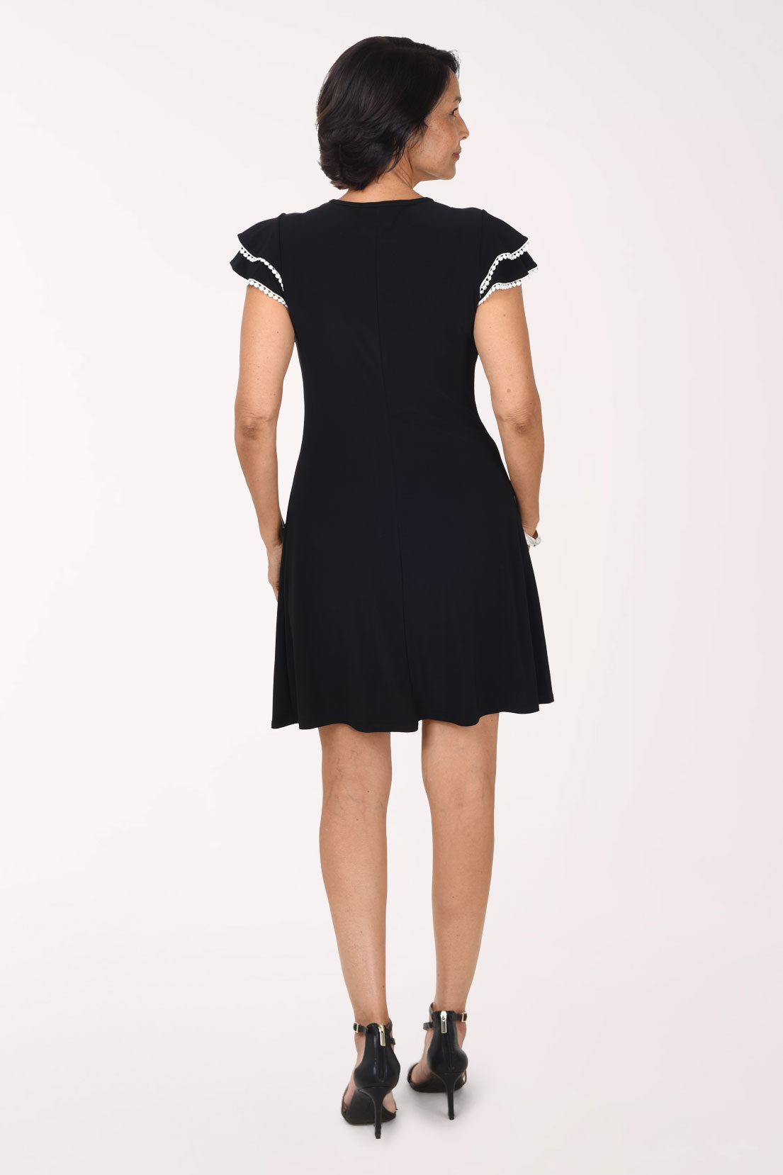 Back view of the black Ric Rack Trim dress showing the white-trimmed flutter sleeves and the flared skirt
