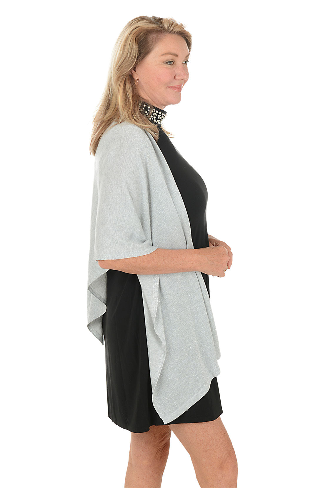 Woman wearing a black dress with a light gray cardigan on a white background. Side shot.