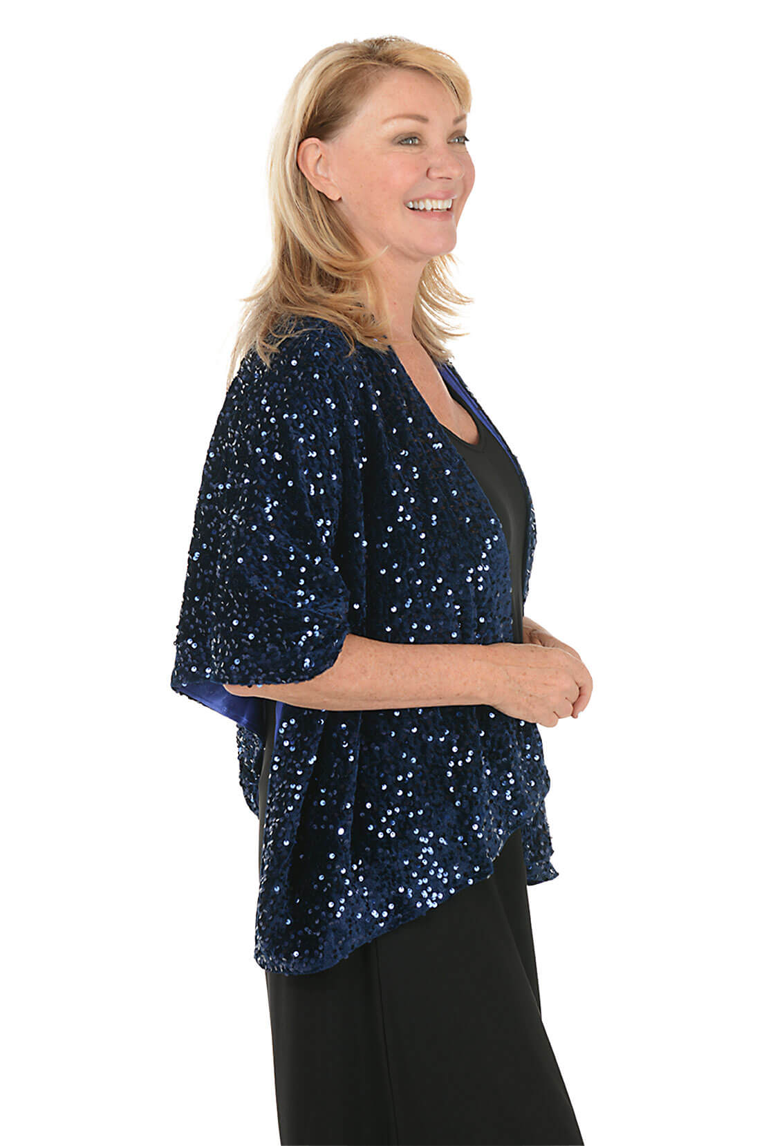 Woman wearing a black dress with a blue sequin shawl on a white background. Side shot.