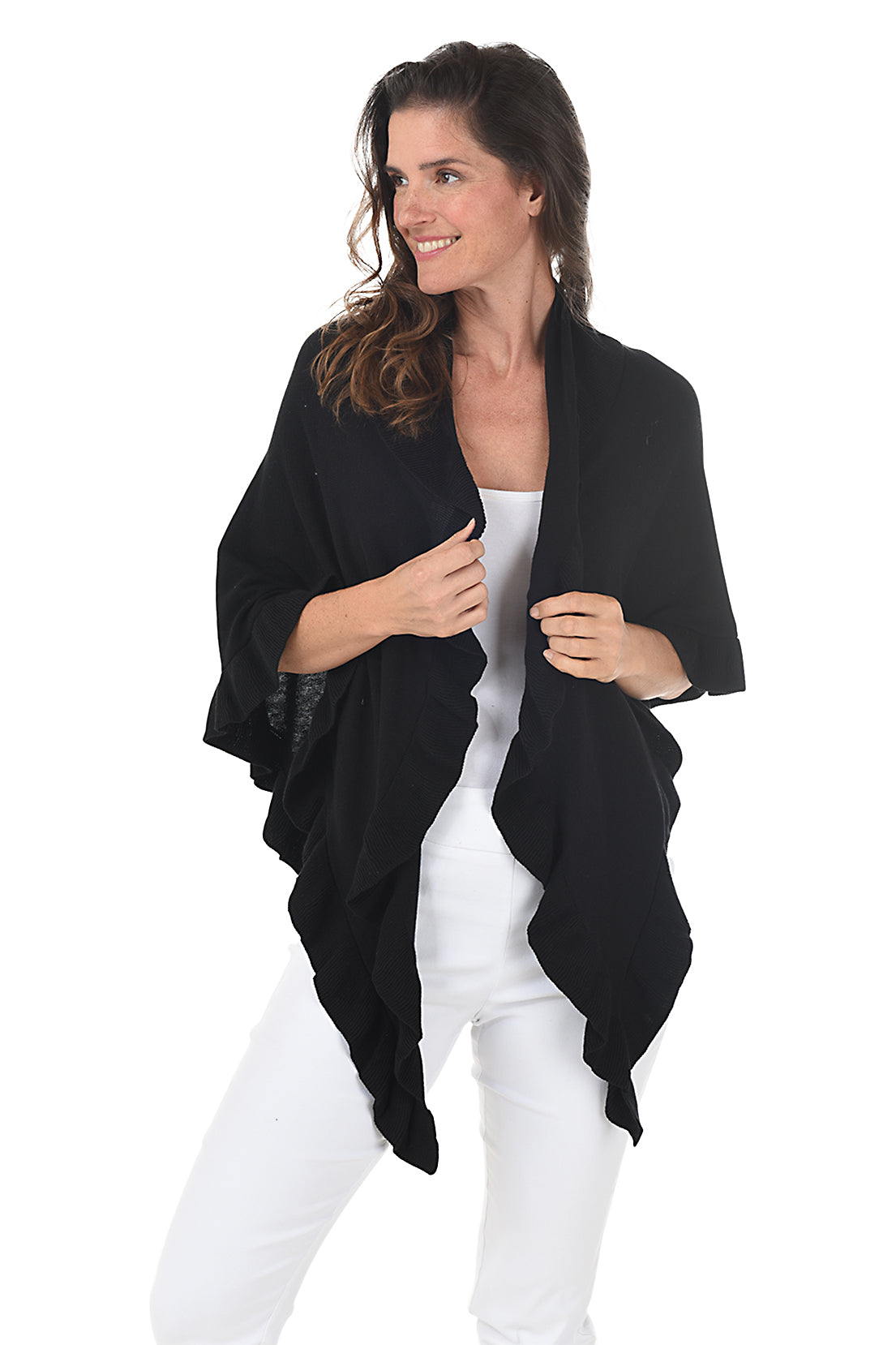 A woman wearing a black open front wrap sweater with ruffled rib-knit trim over a white top and white pants.
