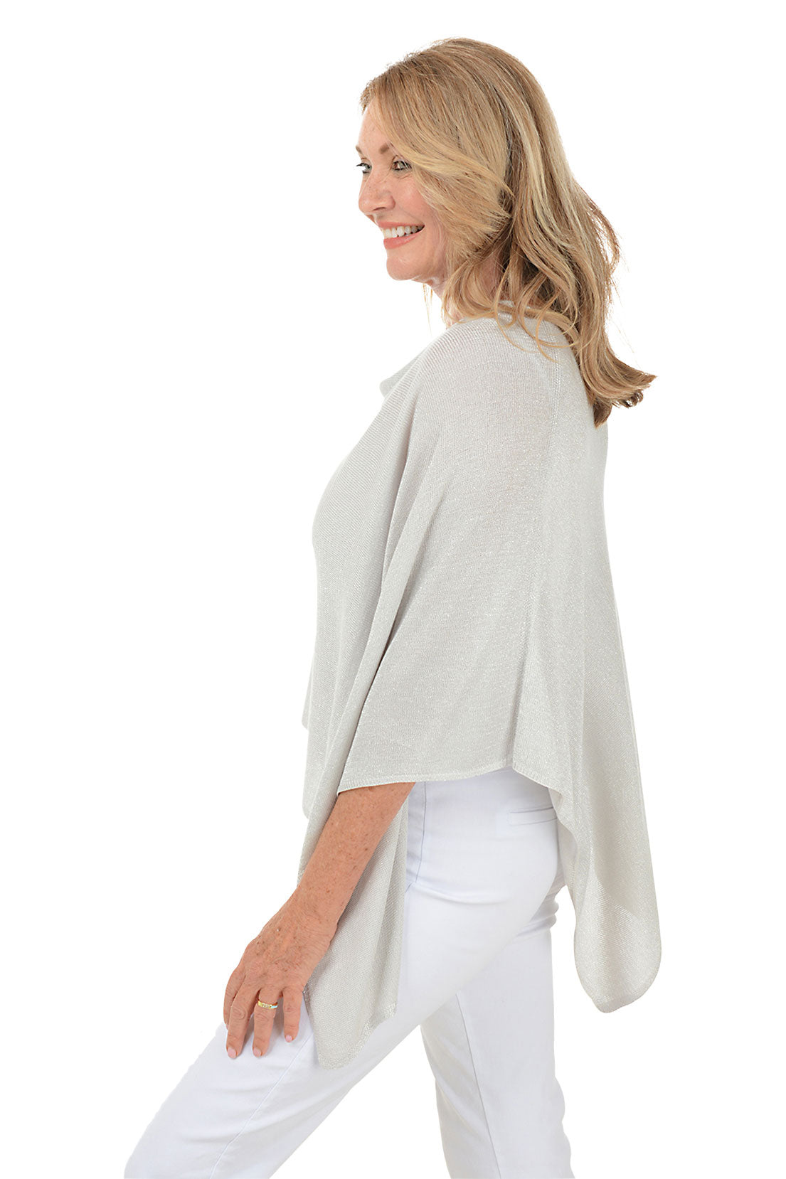 Woman wearing a light gray poncho over a white outfit on a white background. Side shot.