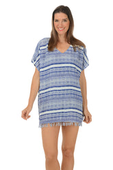 A woman wearing a blue and white striped fringe cover-up with a V-neck and short, loose dolman sleeves.