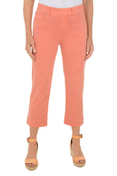 A front shot of a model wearing a pair of orange denim kick flare crop pants with a mid-rise waist and belt loops.