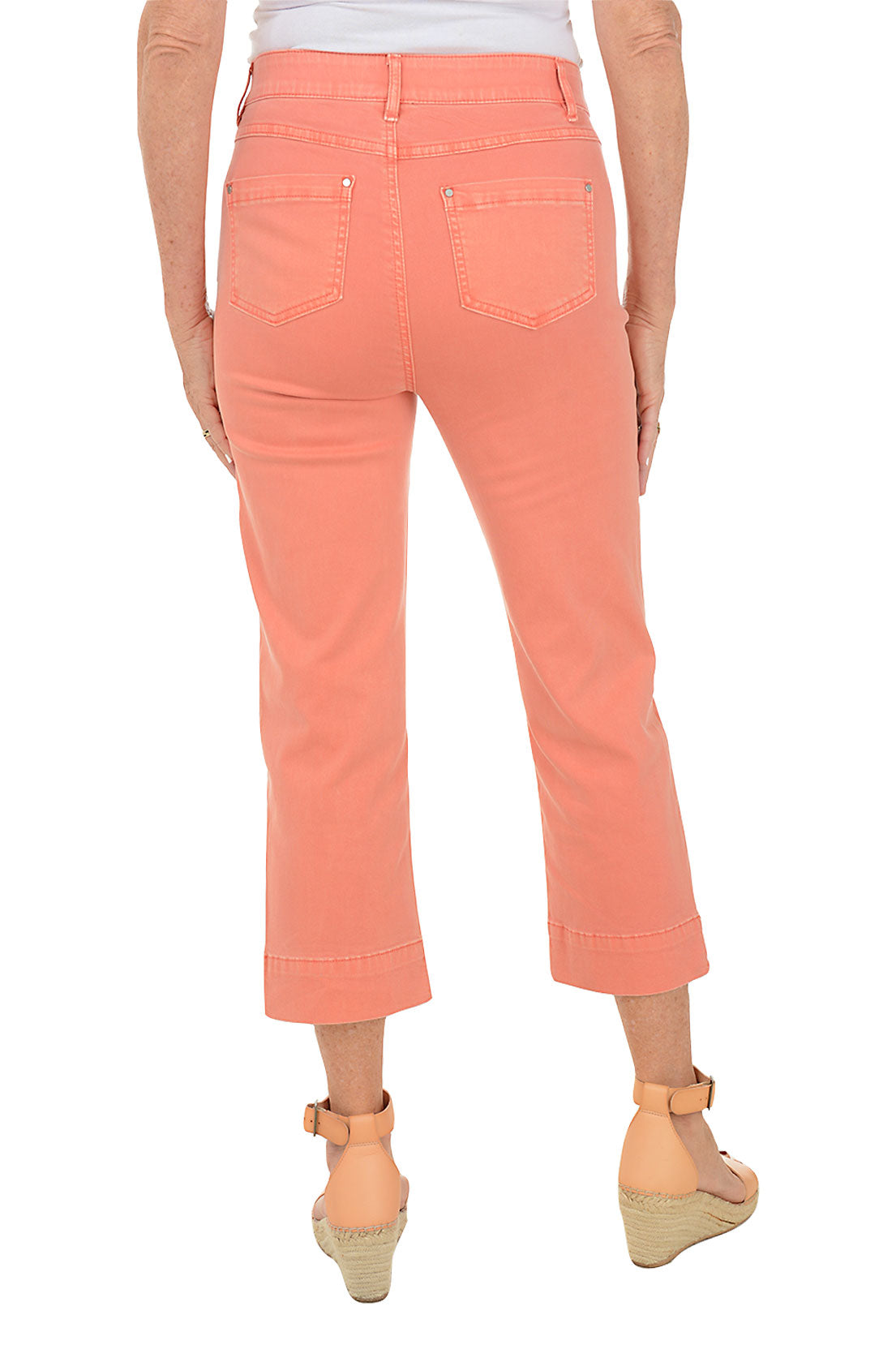 A back shot of a model wearing a pair of orange denim kick flare crop pants with a mid-rise waist and belt loops.